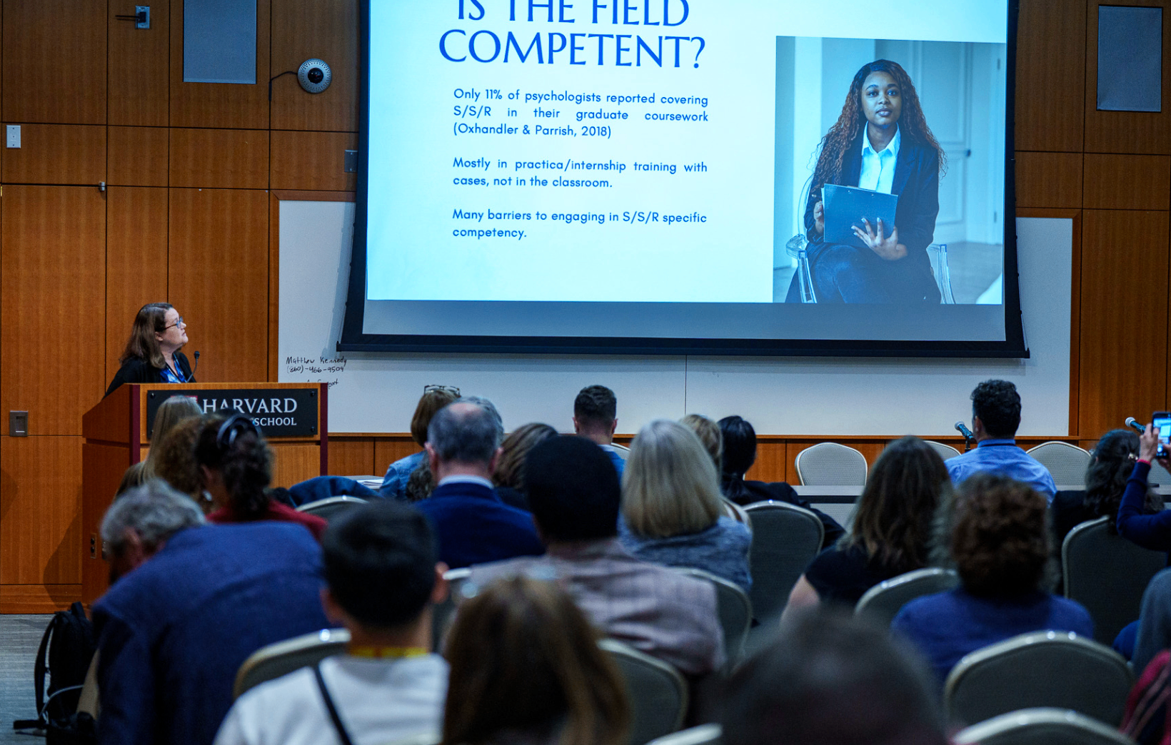 Speaker presenting research slides to a seated audience