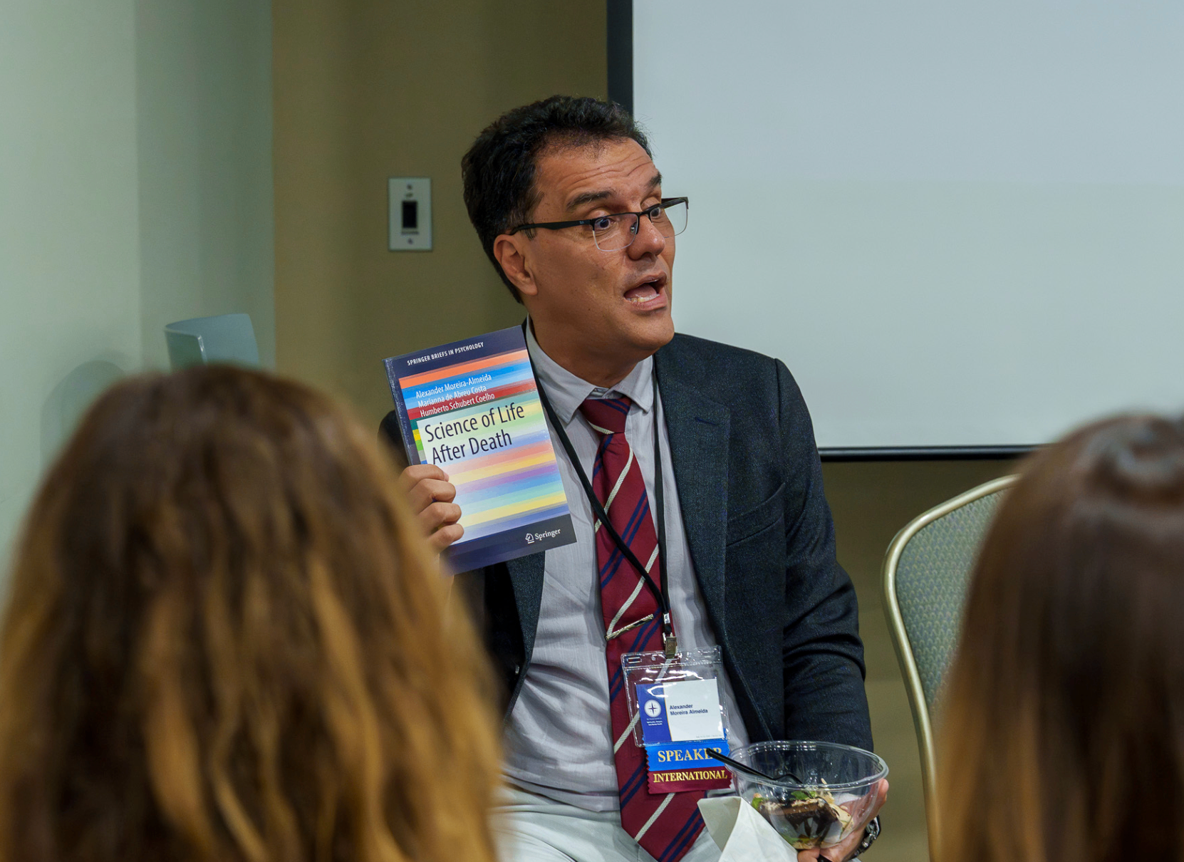 Speaker holding a book during a smaller summit discussion